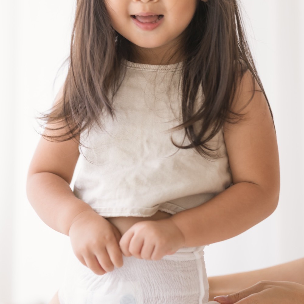 A smiling toddler standing in Little Rei pull-up pants
